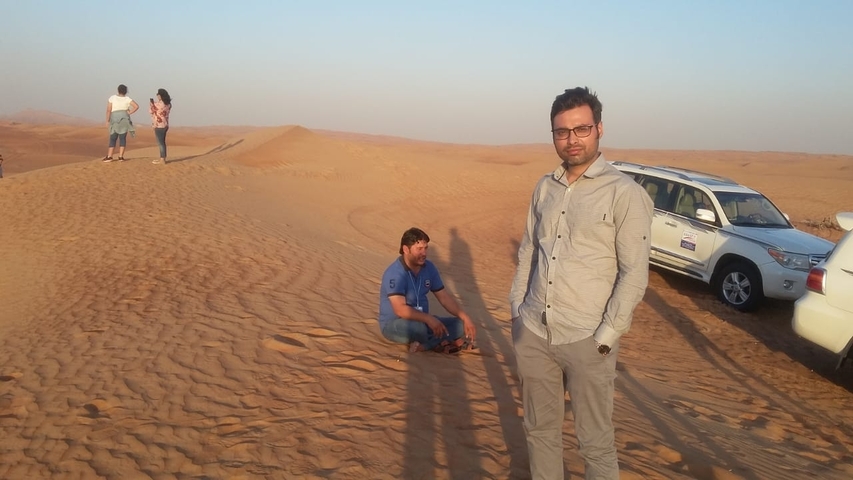 Group of people in a desert landscape with vehicles.
