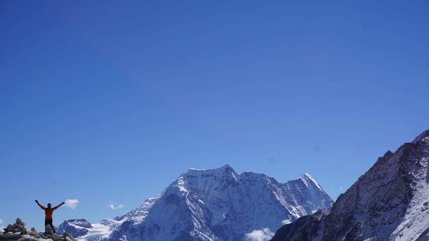 Mountains with a person raising their hands in celebration.