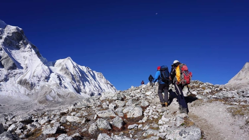 People trekking in a snowy mountainous landscape.