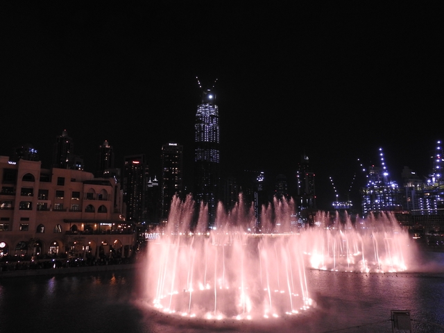Fountain show with city skyline at night.