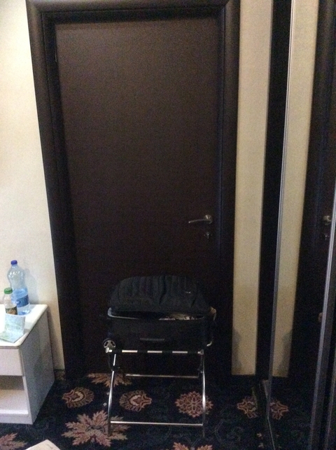 Closed door inside a room with a suitcase and water bottle.