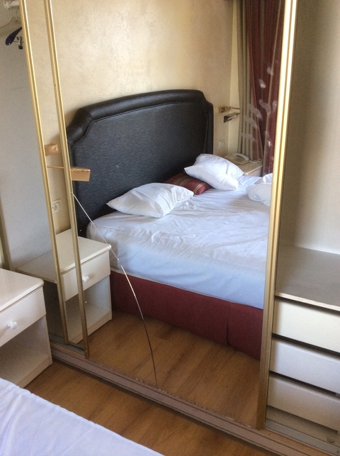       Unmade bed in a hotel room with mirrored doors.
  