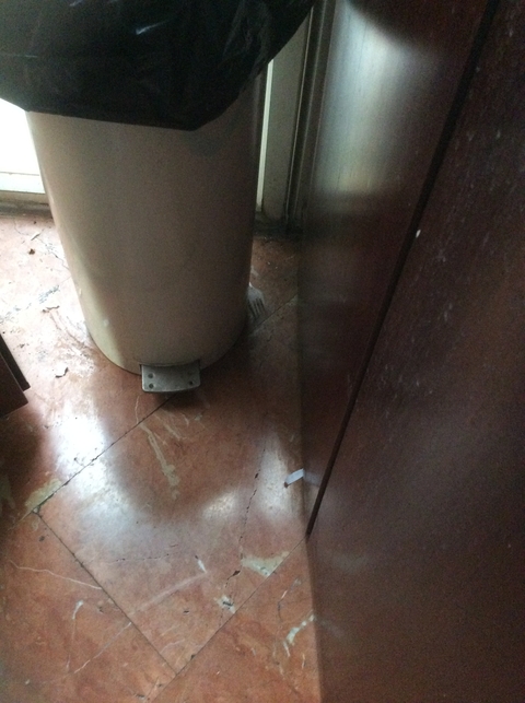 View of a garbage bin in a poorly lit area.