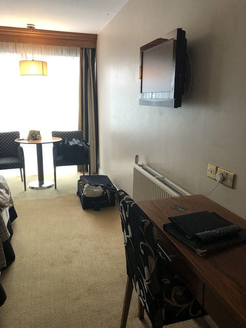 Interior of a hotel room with a table and desk.
