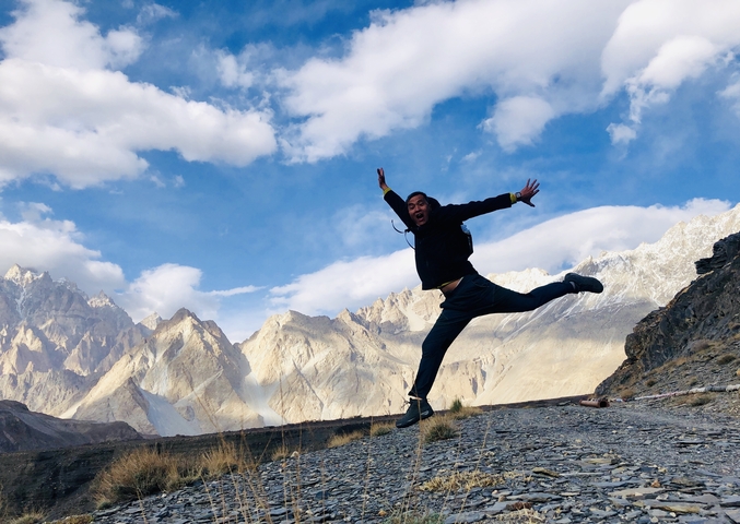       Person jumping joyfully with mountains in the background.
  