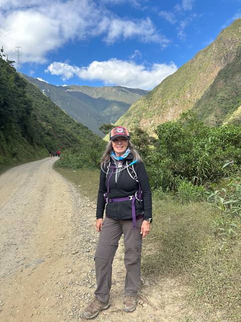A woman posing on a mountain trail with a scenic view in the background.