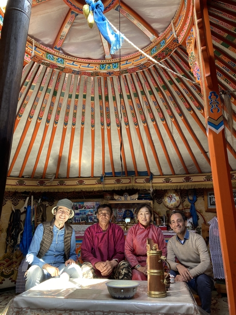 Group of people inside a traditional yurt with colorful interior details.