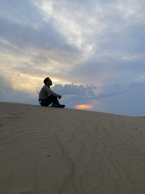 Person sitting on sand dune watching the sunset