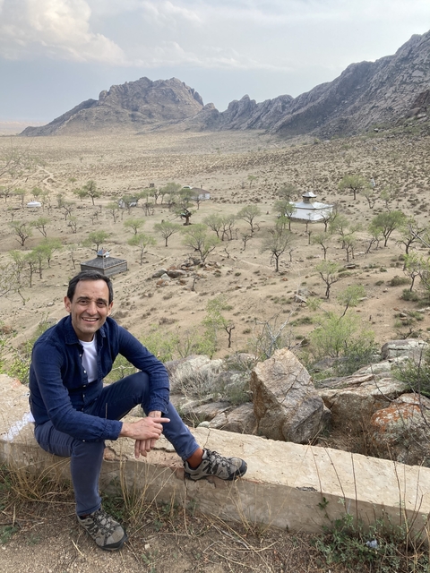       Man sitting on a hill overlooking a valley
  