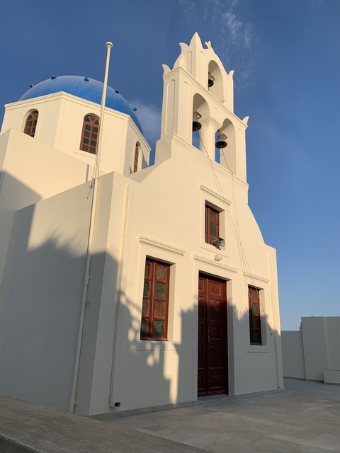 Whitewashed church under a clear sky with shadows.