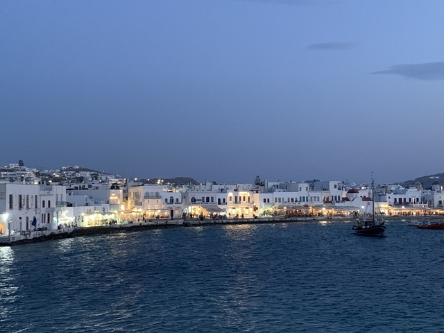 Coastal town with lights reflecting on the water at dusk.