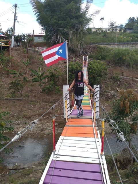       Woman walking on a colorful bridge with a flag.
  
