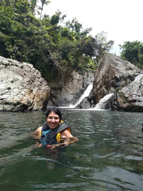       Woman in a life vest by a waterfall.
  
