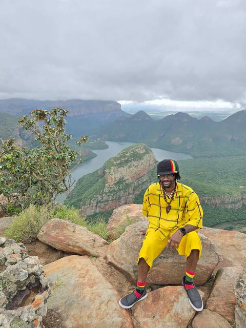       Person in colorful attire sitting on rocks overlooking a canyon.
  