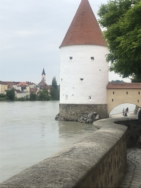 White tower by a river with a church in the background.