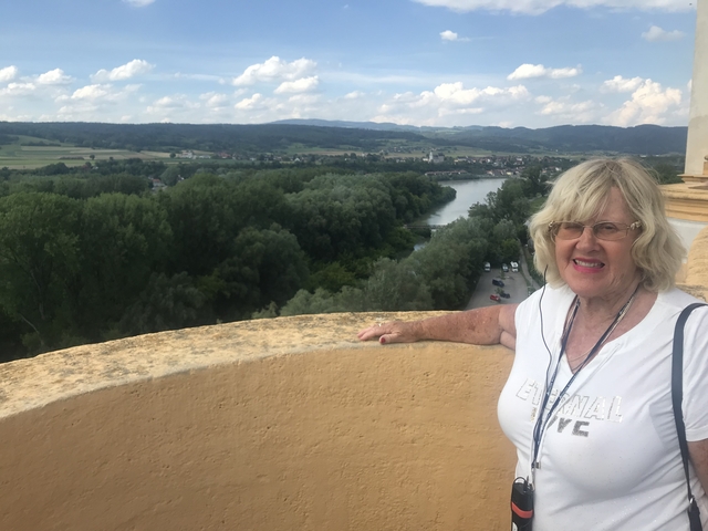 A woman posing at a scenic lookout with a river view.