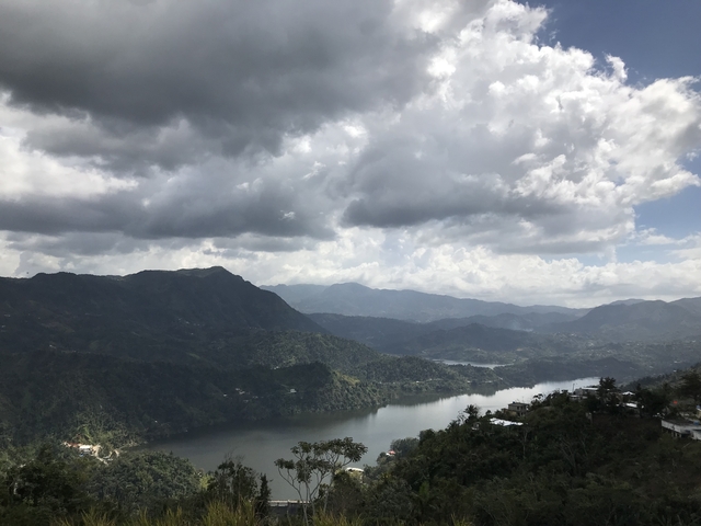       Scenic view of mountains and a river under a cloudy sky.
  