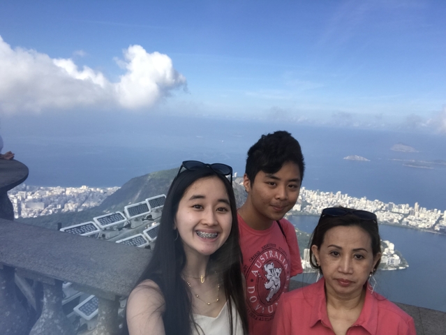 Three people posing with a coastal city view in the background.