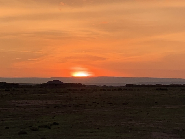 Sunset over a flat landscape with a silhouette of a building.