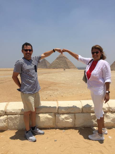       A couple posing with the Pyramids in the background.
  