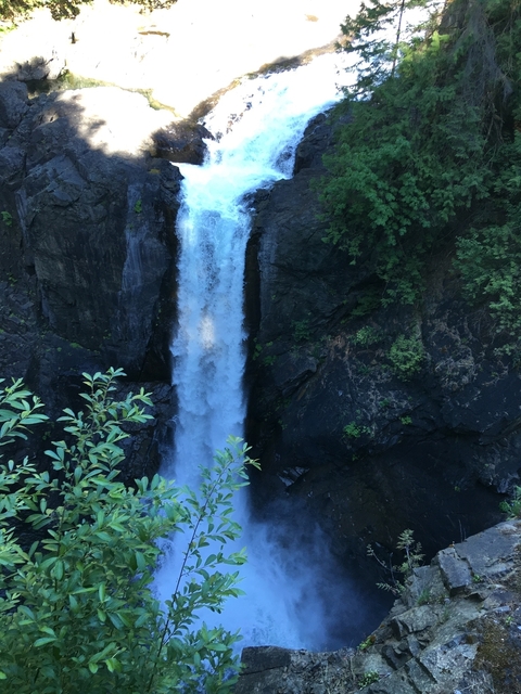 A waterfall cascading between rocky cliffs and greenery.