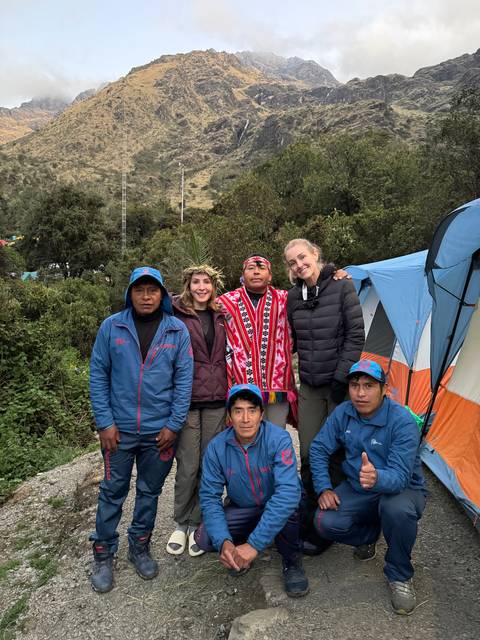       A group of people posing at a campsite with tents in the background.
  