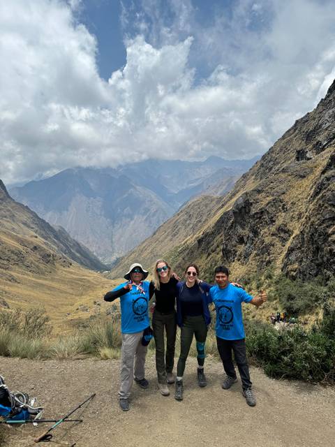       Group of people posing in a mountain landscape.
  