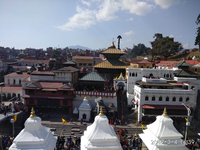       A temple complex with a large crowd and traditional architecture.
  