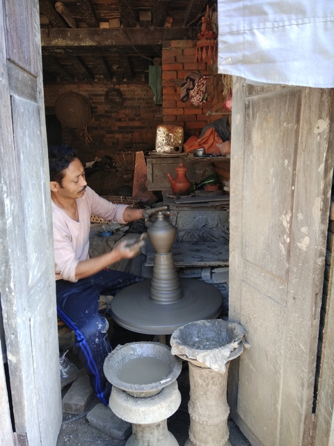       A person working on pottery in a rustic setting.
  