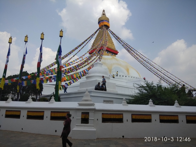      Stupa with prayer flags and people in front.
  