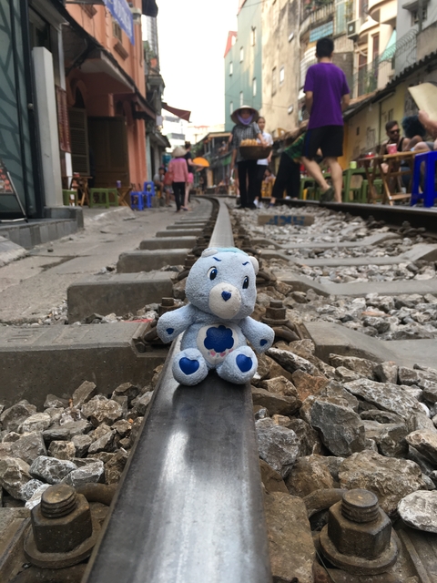 A small teddy bear toy placed on a railway track.