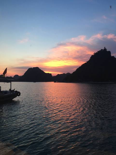 A beautiful sunset view over a bay with silhouetted mountain formations.