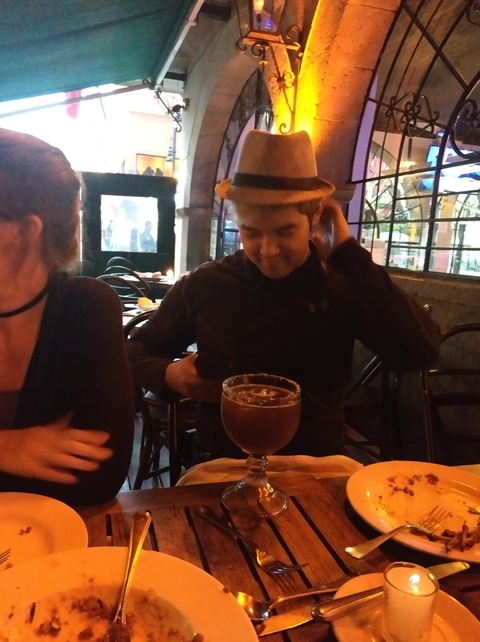 A person drinking a large cocktail in a dimly lit restaurant.