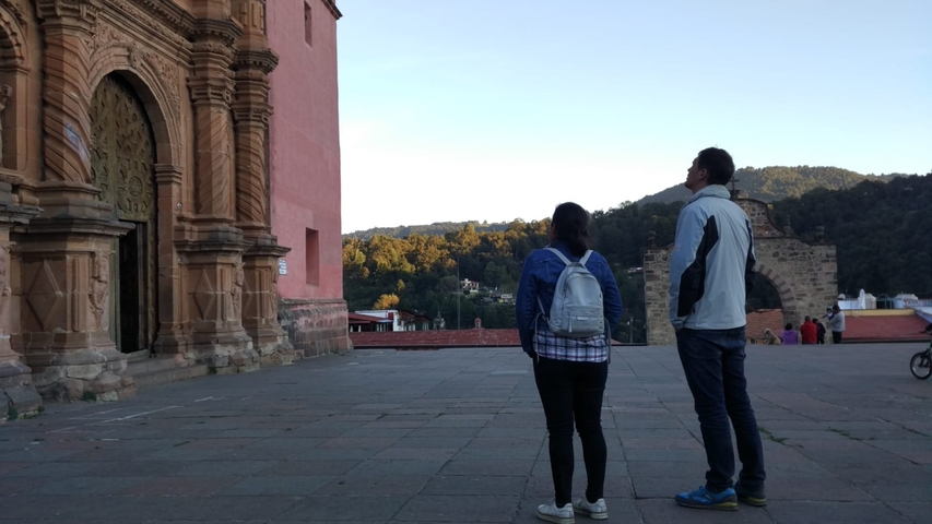 Two people standing near a historical building with an ornate facade.