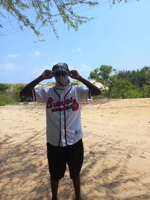       Person standing on sand wearing a sports shirt and scarf.
  