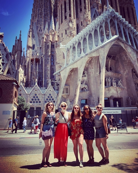 Group of women posing in front of a large, intricate structure.