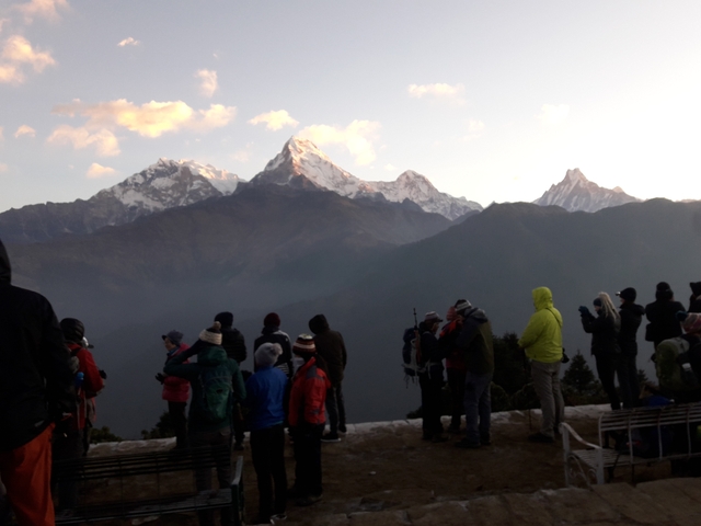 People silhouetted under a sunrise with mountain views.