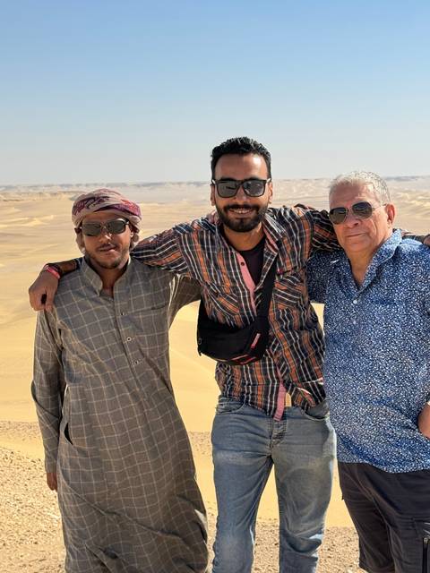       Three people posing in a desert landscape.
  