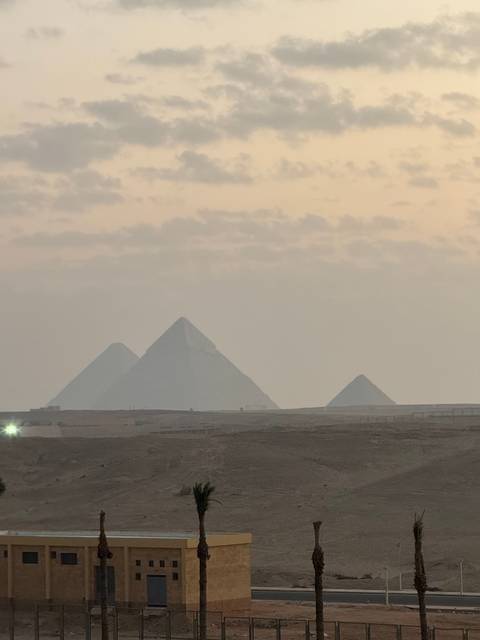       Distant view of pyramids under a cloudy sky.
  