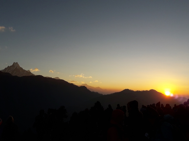 Silhouette of people watching a mountain sunset.