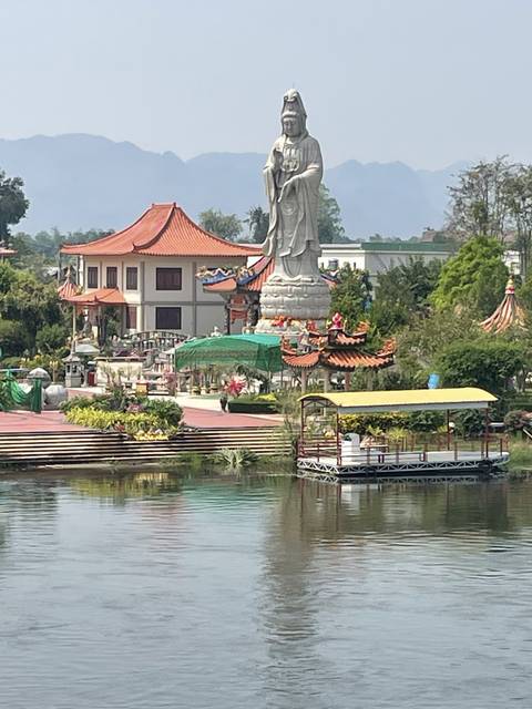       A statue beside a river with nearby buildings.
  