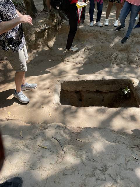       People standing by a rectangular opening in the ground.
  