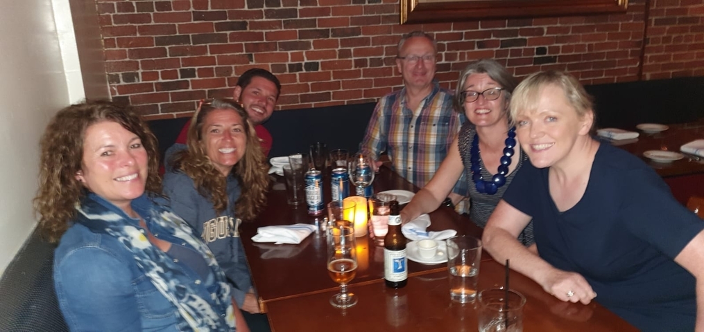 Six people sitting at a table in a cozy restaurant scene.