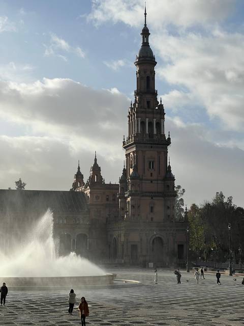 A tall, intricate architectural structure with spires and a fountain in front.