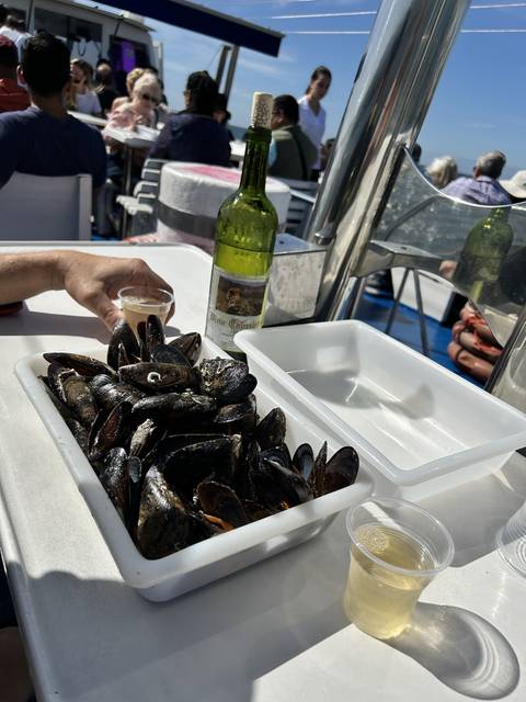       Dinner setting with wine and a bowl of mussels on a table.
  