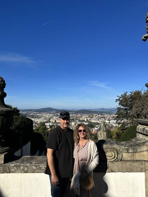 A couple posing with a scenic city view in the background.