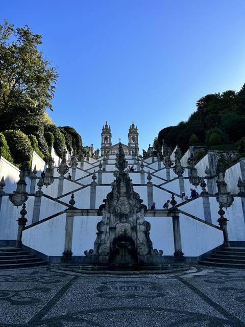 Symmetrical staircase with ornate stonework under a blue sky.