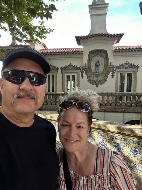       Two people smiling in front of a decorative facade.
  