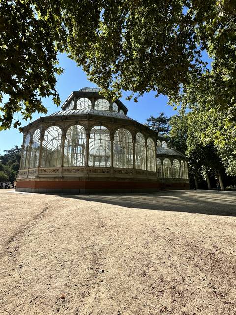 Glass greenhouse structure in a park setting.