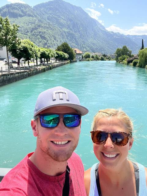       A couple taking a selfie with a mountainous lake view.
  